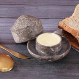 Butter dish with a knife and bread on a wooden surface
