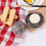 Marble butter dish with lid holding butter, placed on a table with bread and breakfast items.