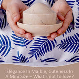 Hands holding a marble butter crock with lid.