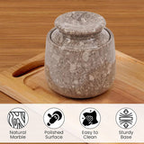 Marble jar with lid on a wooden surface, featuring icons and text about material properties.