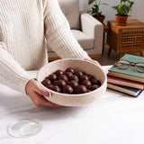 Person holding a bowl of chocolate truffles in a cozy living room setting.