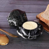 Black marble butter crock with butter served beside bread on a breakfast table.
