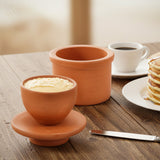 Terracotta Butter Keeper on a wooden table with a cup of coffee and pancakes.