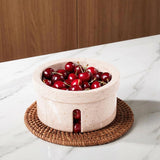 Bowl of cherries on a marble surface with a wooden background