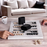 Two people playing a board game on a marble board with a cup of coffee and black containers in the background.