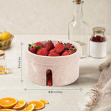 Bowl filled with strawberries on a table with measurements indicated.