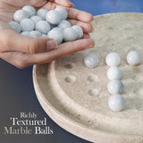 Hand holding marble balls with a textured surface on a stone game