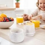 White marble butter crock on a family breakfast table with juice and fruit.