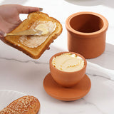 Terracotta butter dish with spreadable butter on a marble surface