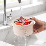 Marble-textured portable sink with strawberries being washed under running water from a faucet.