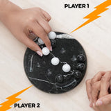 Two hands playing a marble game on a black marble board with 'Player 1' and 'Player 2' labels.