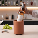 Person holding a bottle of Rosé Reserve wine in a terracotta holder with a kitchen background.