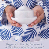 Hands holding a mini white marble butter crock with lid