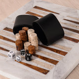 Black dice cups, wooden dice, and dice on a marble surface
