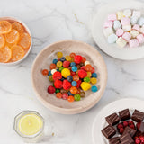 Assorted candies including gummy bears, chocolate pieces, and lemon slices on a marble surface.