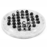 A black balls arranged on a round white marble board against a plain white background