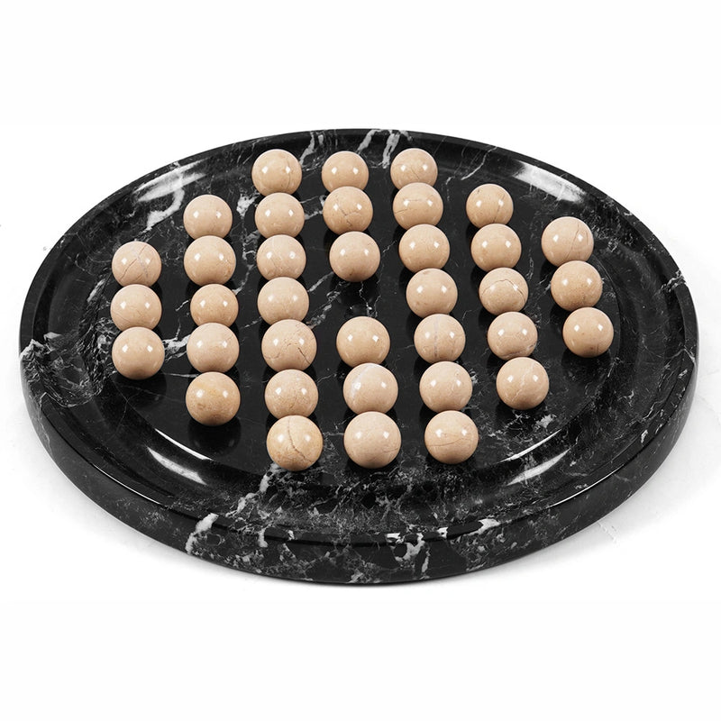 A set of 36 polished beige stone playing balls arranged on black marble game board with white veining, photographed on a clean white background.