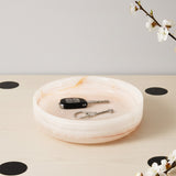 Marble-patterned tray with keys on a light surface with black circular marks