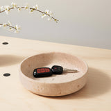 Dish with keys on a light wooden surface, with a branch of white flowers in the corner.