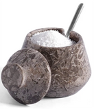 A  marbled salt and pepper Cellar with its lid off, filled with coarse white salt and a metal spoon, on a white background.