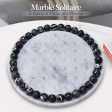Marble Solitaire game with black and white marbled balls on a marble surface