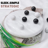 White marble surface with black and white stones, green leaves, and 'Sleek.Simple.Strategic' text.
