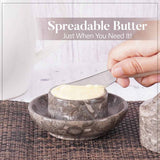 Marble butter keeper with spreadable butter being served using a knife. 