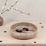 Decorative stone bowl with keys on a wooden surface, branch with white flowers in the background