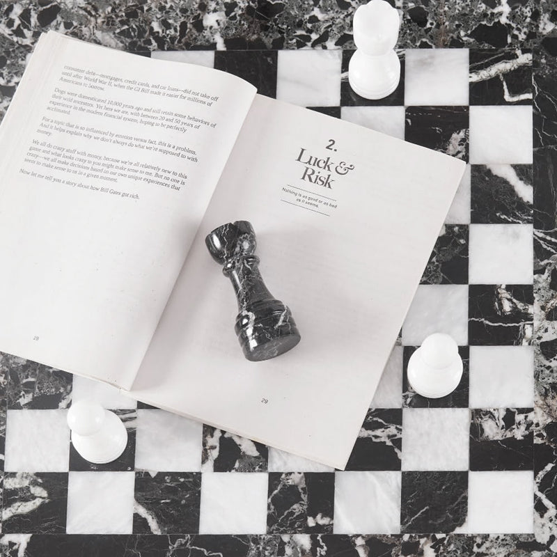 Open book with a chess piece on a marble chessboard