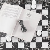 Open book with a chess piece on a marble chessboard