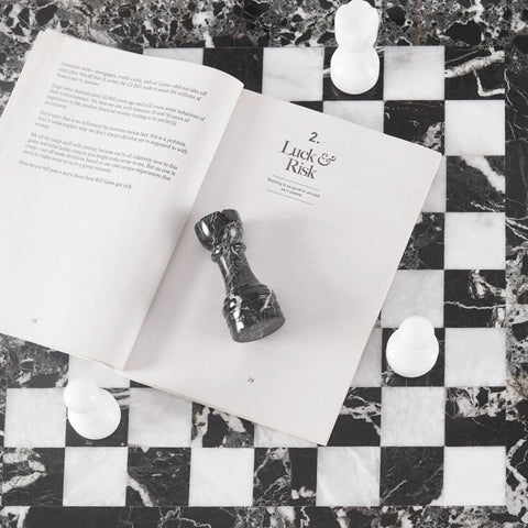 Open book with a chess piece on a marble chessboard