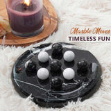 Marble moves game with marbles on a black marble board, candle in the background