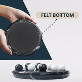 Black marble coaster with felt bottom held by a hand, showing its texture.