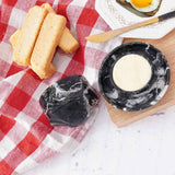 Black marble butter crock with butter served alongside toast on a breakfast table.