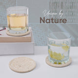 Two glasses with lemon slices on travertine stone coasters, with 'Unique by Nature' text.