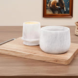 White marble butter crock with lid placed on a wooden board on a table.