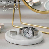 Silver watch on a white coaster with 'Chic Catch'