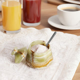 Decorative salt cellar with spoon on a table with drinks and coffee.