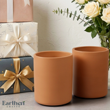 Two terracotta pots on a surface with wrapped gifts and flowers in the background, featuring the brand 'Earthen Crafts'.