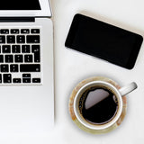 Laptop, smartphone, and coffee cup on a white surface