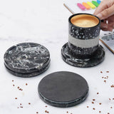 Black marble coasters with a striped mug of coffee on a light surface.