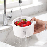 Handcrafted white marble berry bowl with footed base and side drainage openings,