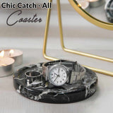 Marble coaster with a watch and ring holder on a white surface with candles and a mirror in the background.