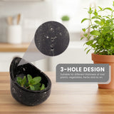 Black three-hole stripper bowl with green plants on a wooden surface, blurred background