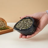 Hand holding a bowl of dried rosemary with bread and rosemary sprigs on a beige background