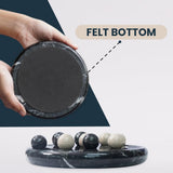 Black marble game with felt bottom held by a hand, showing its texture and use.