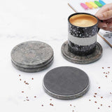 Set of stone coasters with a cup of coffee on a white surface.