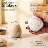 A hand holds a white salt and pepper shaker