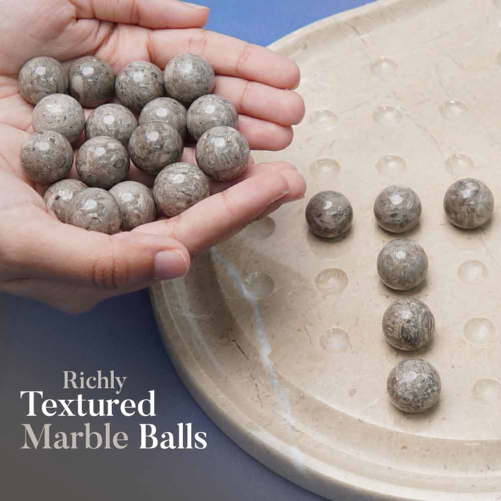 Hand holding marble balls with a plate of marble balls on a blue background