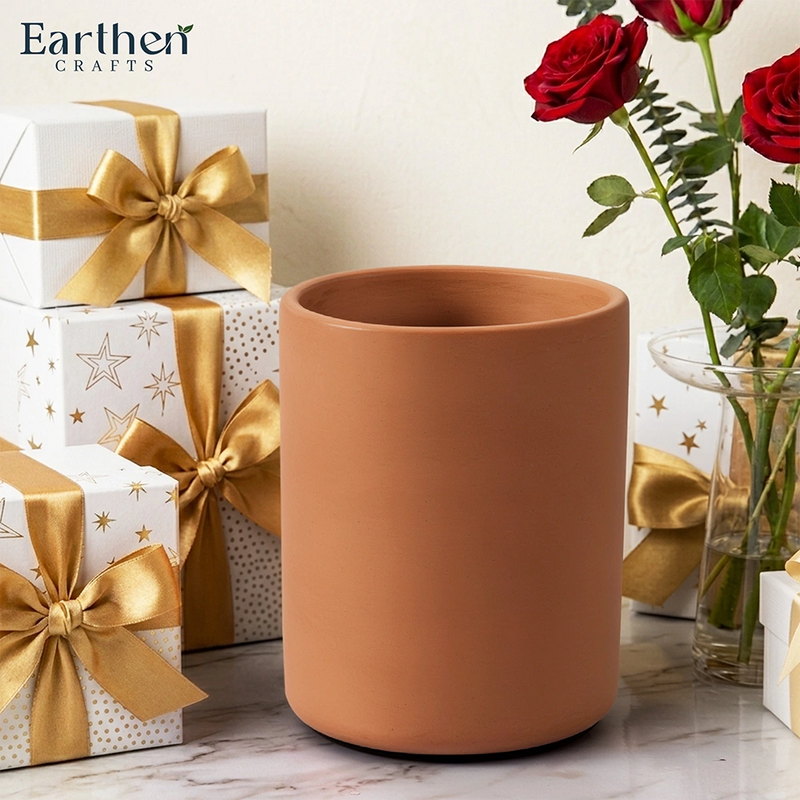 Terracotta utensils holder with gift boxes and red roses on a light background